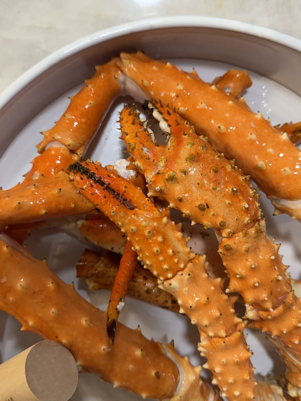 Image of Mega Colossal Alaskan King Crab Legs (6/9) - Alaskan King Crab legs in a white container on a light-colored surface